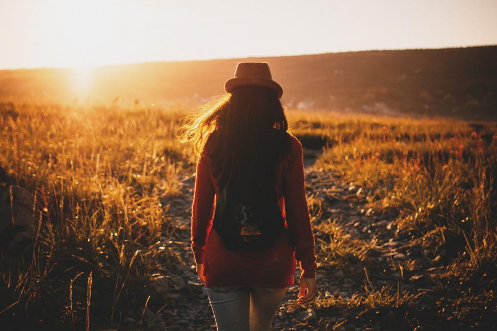Free Image of Woman Walking Through Field at Sunset 