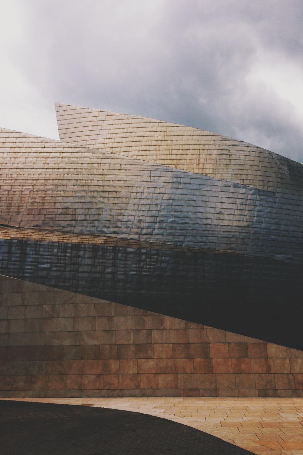 Free Image of Large Building With Curved Roof Under Cloudy Sky 