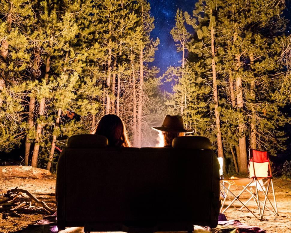 Free Image of Two People Sitting on a Couch in the Woods at Night 
