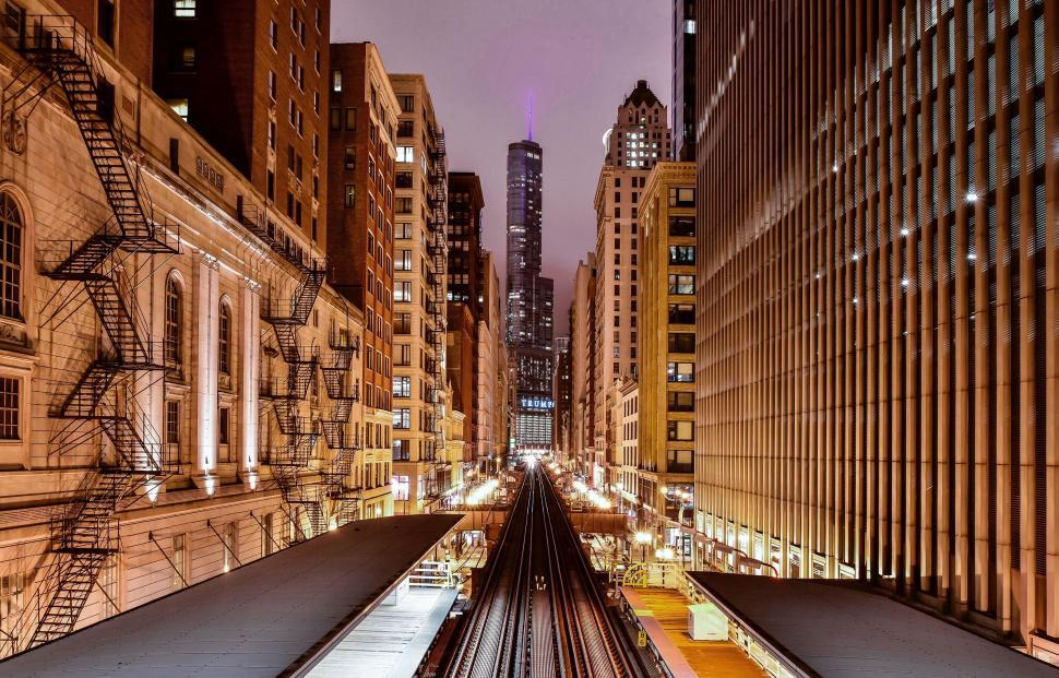 Free Image of Train Traveling Through City Next to Tall Buildings 