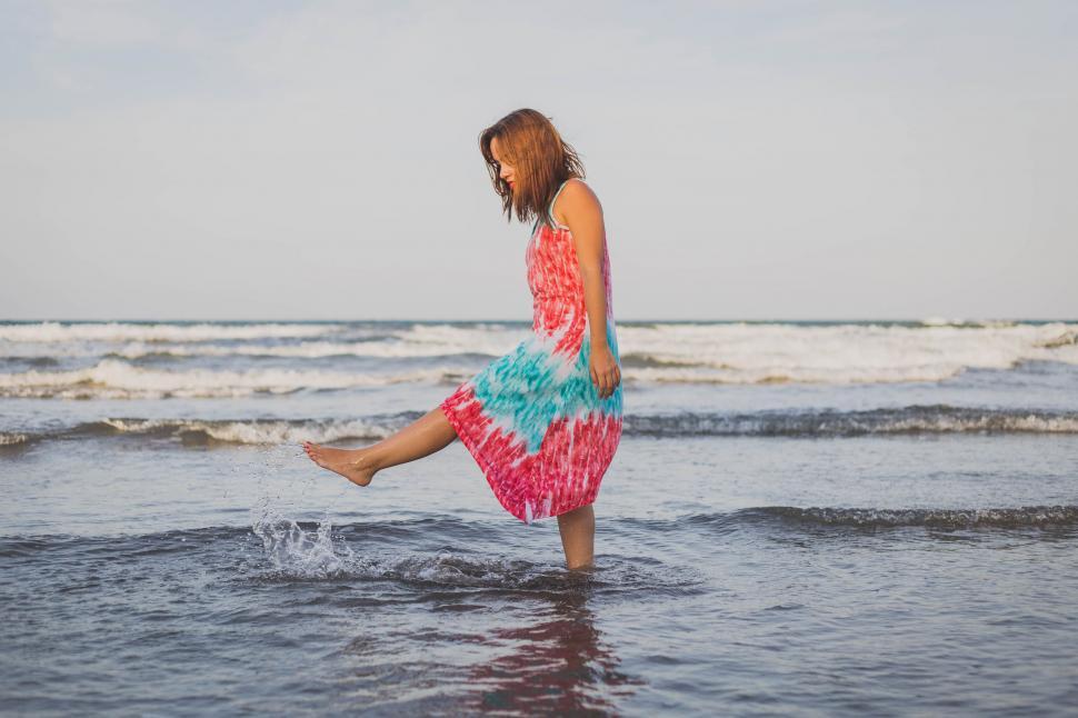 Free Image of Woman Standing in Ocean With Feet in Water 