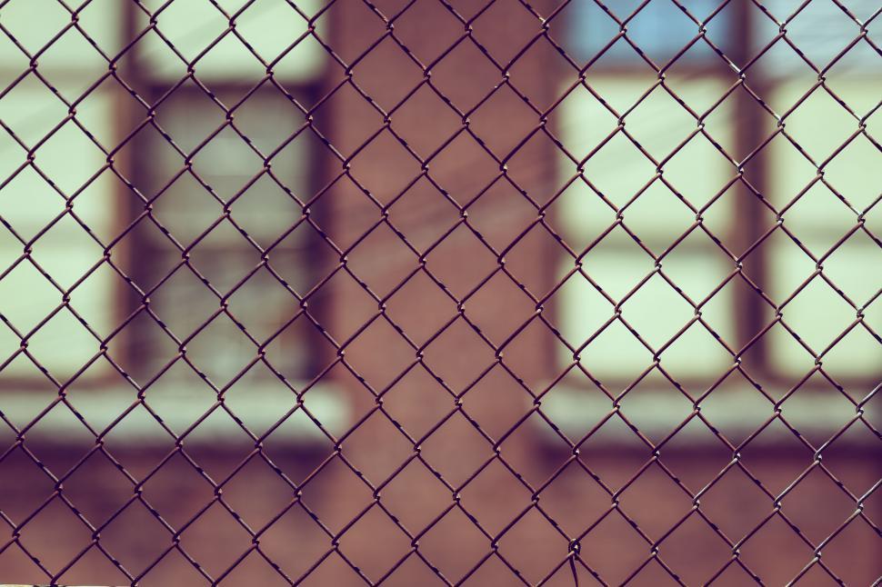 Free Image of Chain Link Fence Close Up With Building in Background 