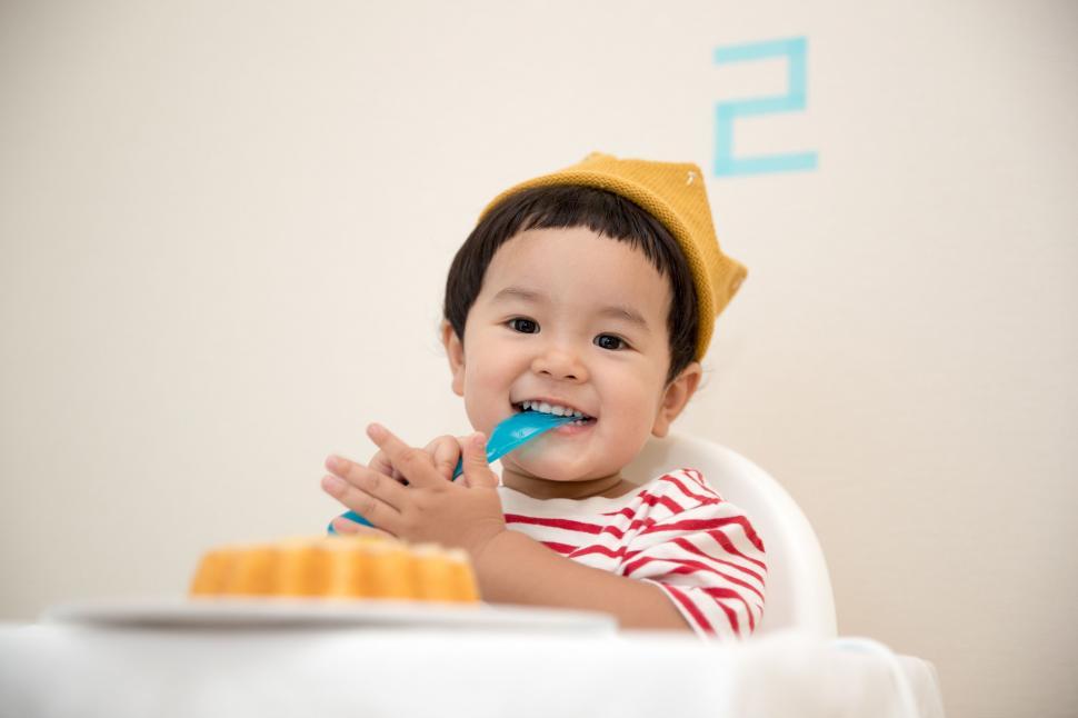 Free Image of Little Boy Sitting in High Chair Brushing Teeth 