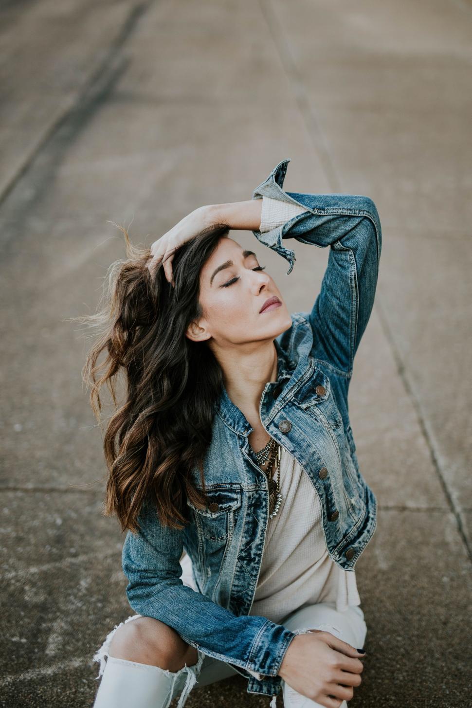 Free Image of Woman Sitting on Ground in Jean Jacket 