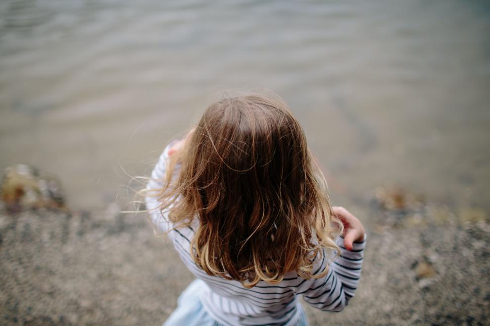 Free Image of Young Girl Standing on Beach by Water 