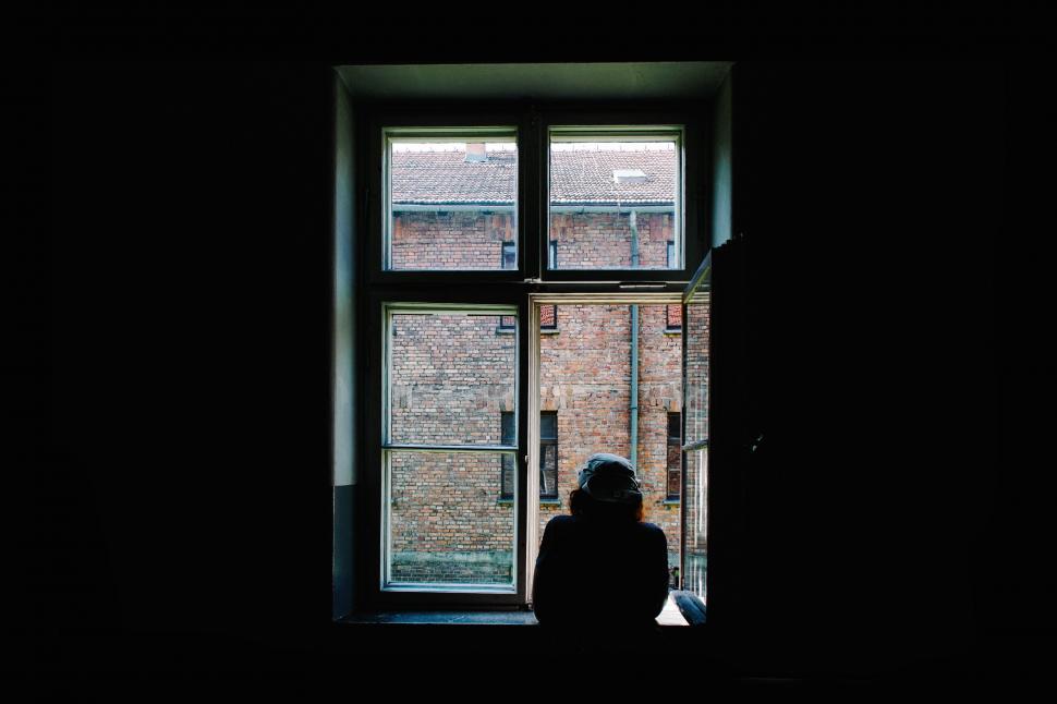 Free Image of Person Standing in Front of Window in Dark Room 