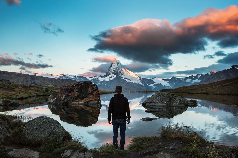 Free Image of Man Standing in Front of Lake With Mountain Background 