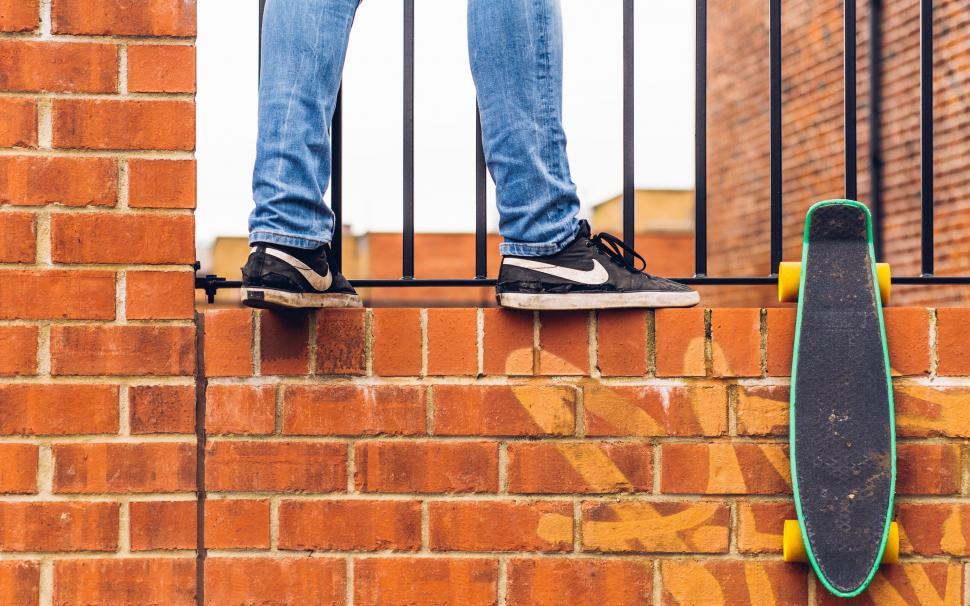 Free Image of Person Standing on Top of Brick Wall With Skateboard 