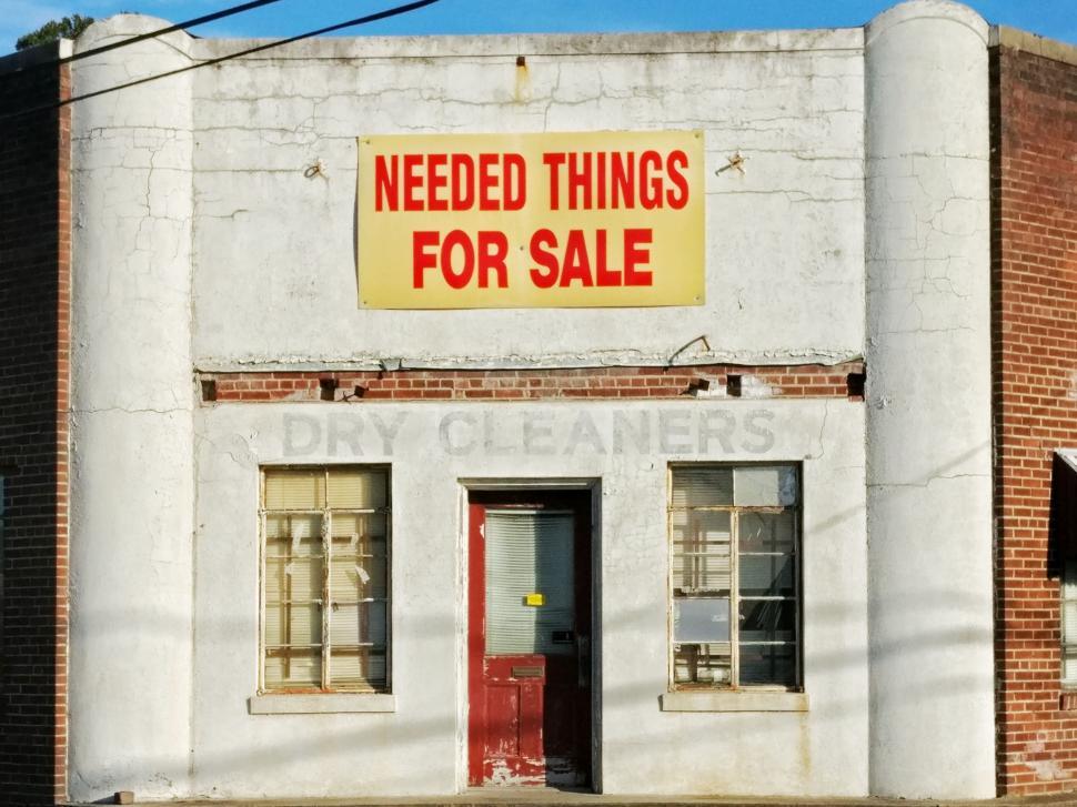 Free Image of White Building With Red Door and Yellow Need Things for Sign 