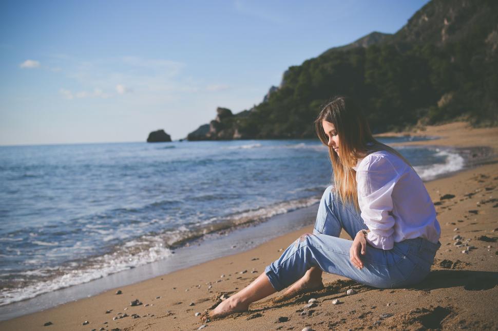 Free Image of Woman Sitting on Beach by Ocean 
