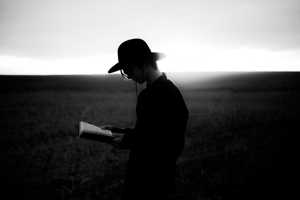 Free Image of Man Standing in Field Reading a Book 