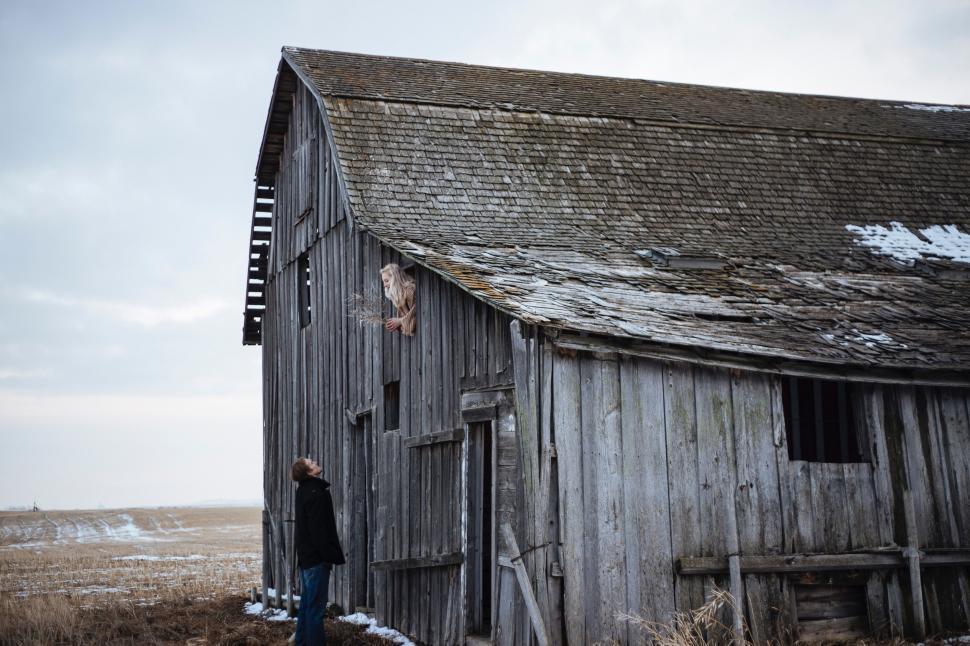 Free Image of Man Standing Outside of an Old Wooden Barn 