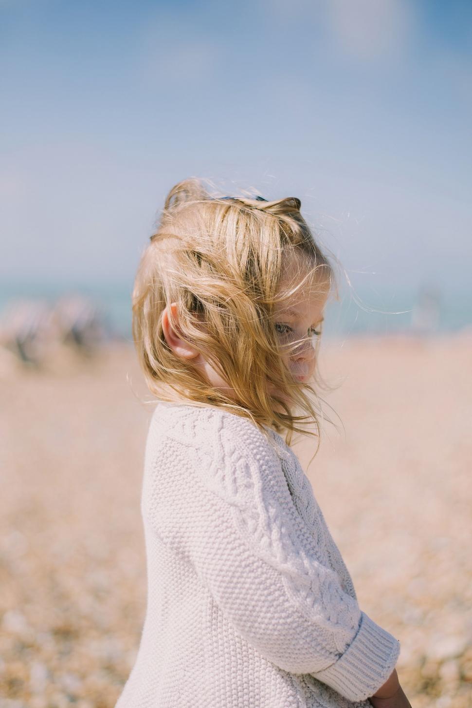 Free Image of Little Girl Standing on Sandy Beach 