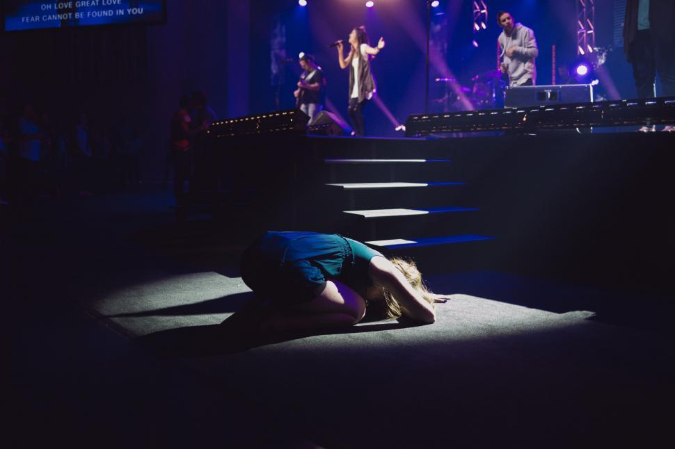 Free Image of Person Laying on Ground in Front of Stage 