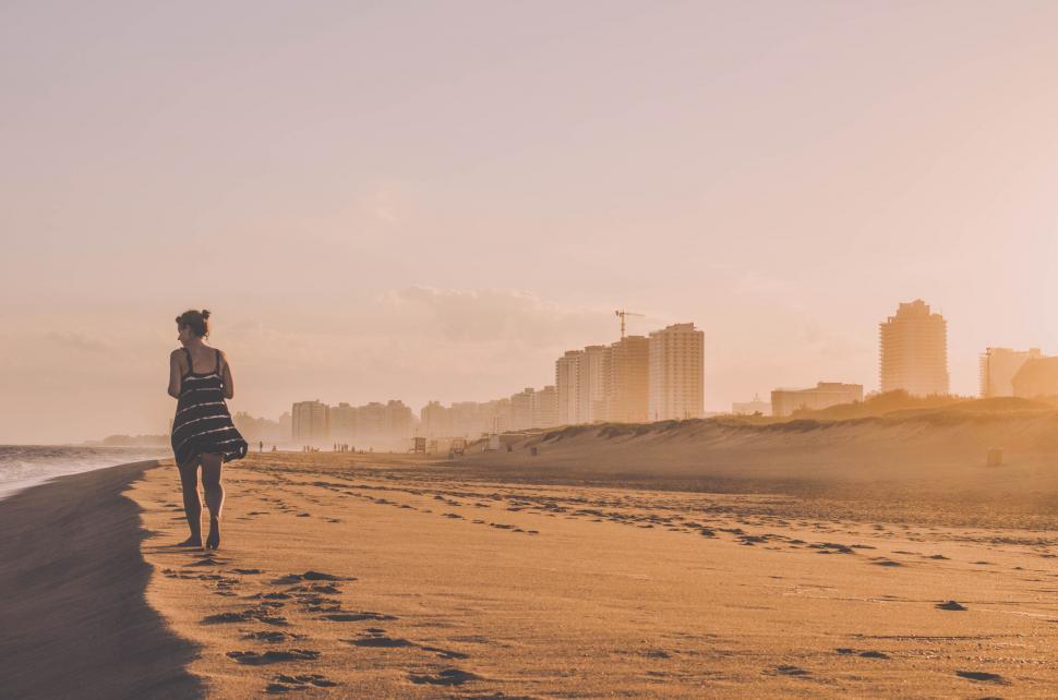 Free Image of Woman Walking Along Beach Beside Ocean 
