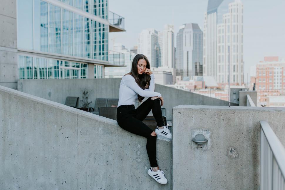 Free Image of Woman Sitting on Ledge in City 