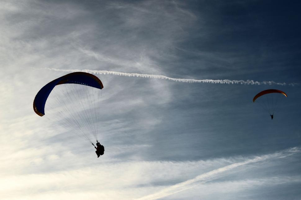 Free Image of Two People Parasailing in the Sky on a Cloudy Day 