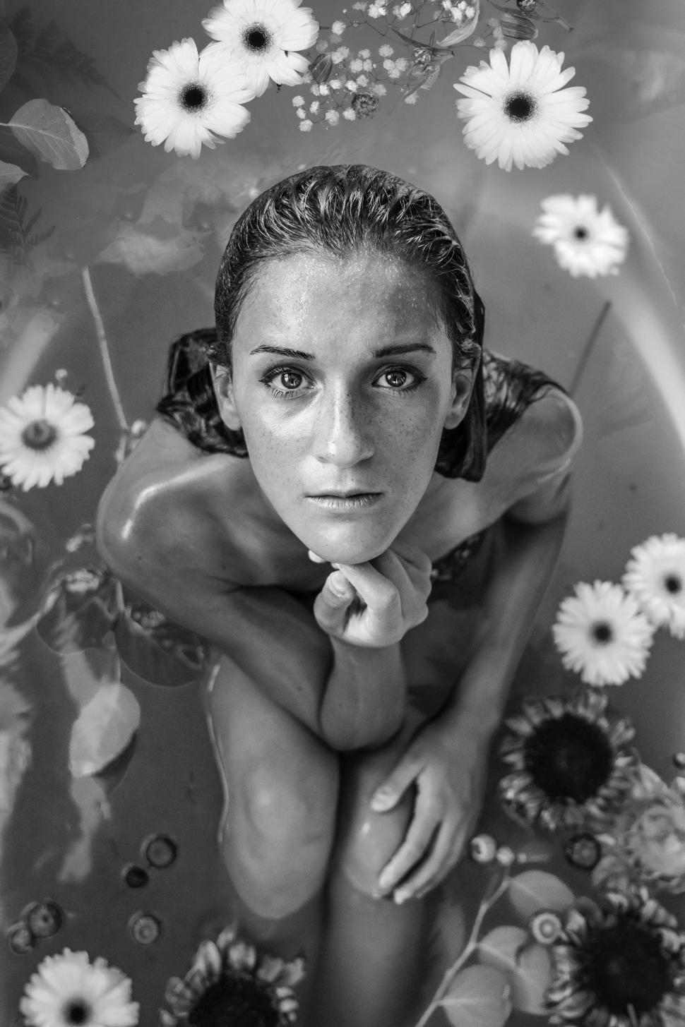 Free Image of Woman Sitting in Tub With Surrounding Flowers 