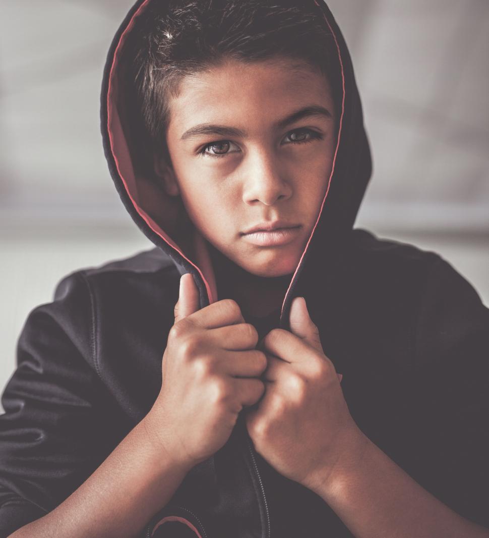 Free Image of Young Boy Wearing Hoodie Holding Pair of Scissors 