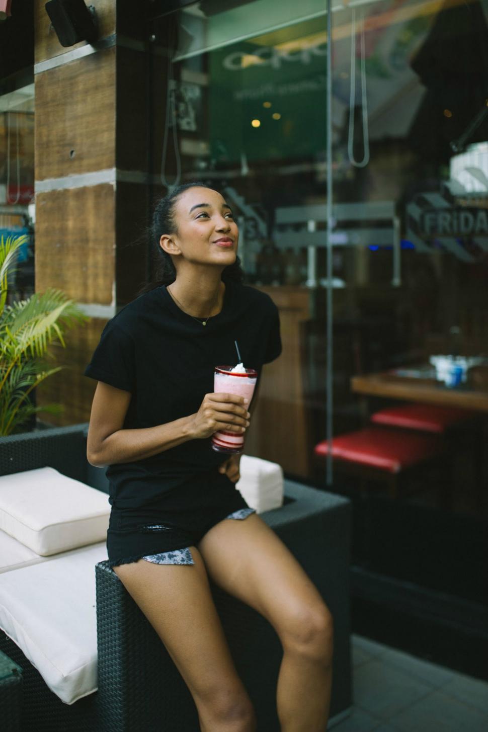 Free Image of Woman Sitting on Bench With Drink 