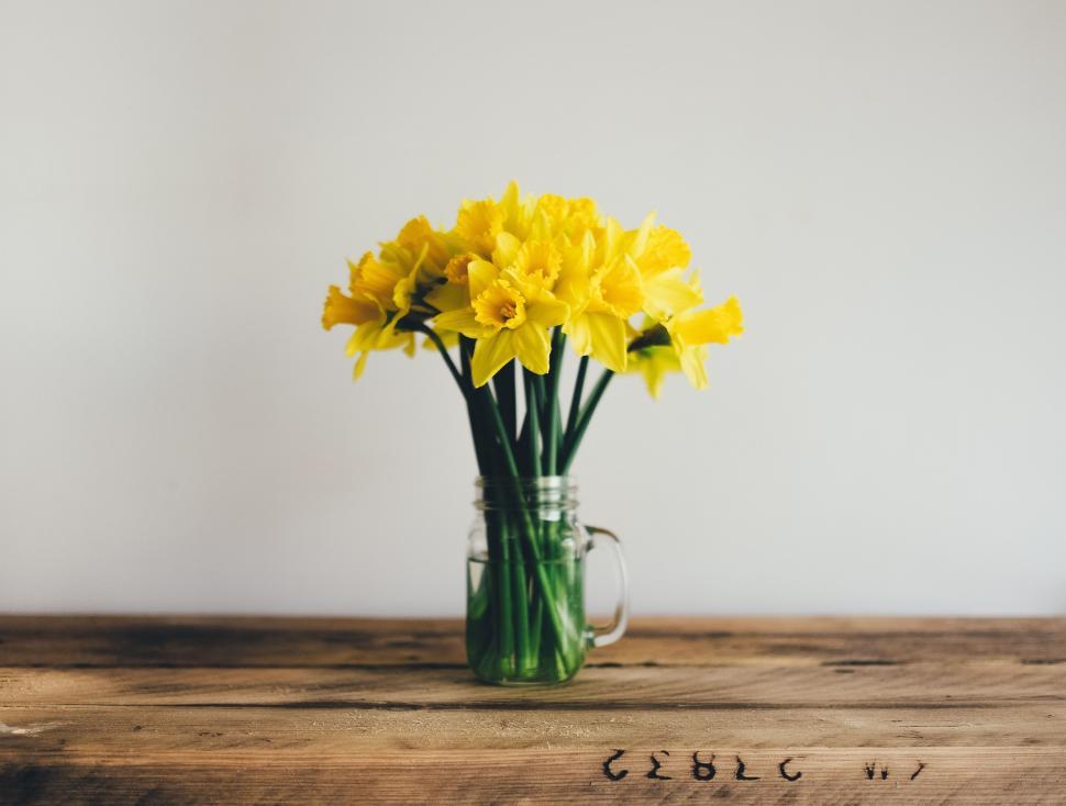 Free Image of Vase Filled With Yellow Flowers on Wooden Table 