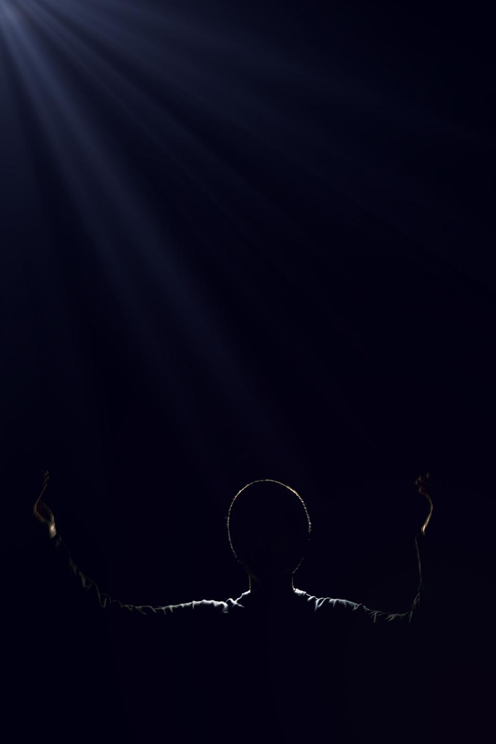 Free Image of Person Standing in the Dark With Arms Raised 