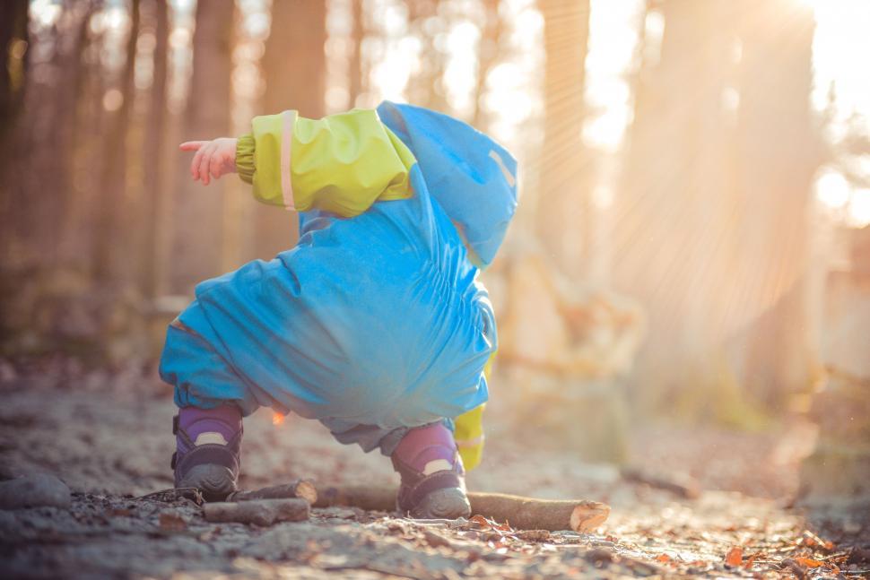 Free Image of Small Child in Blue and Yellow Raincoat Playing in Woods 