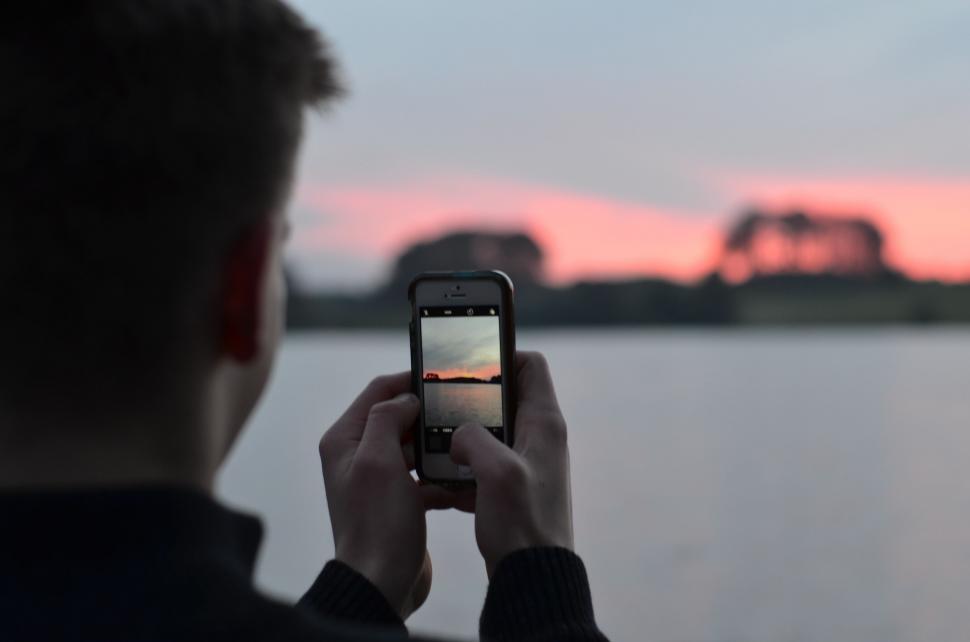Free Image of Man Taking Picture of Sunset With Cell Phone 