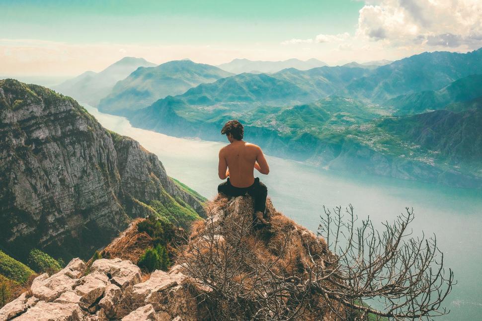 Free Image of Man Sitting on Mountain Overlooking Lake 