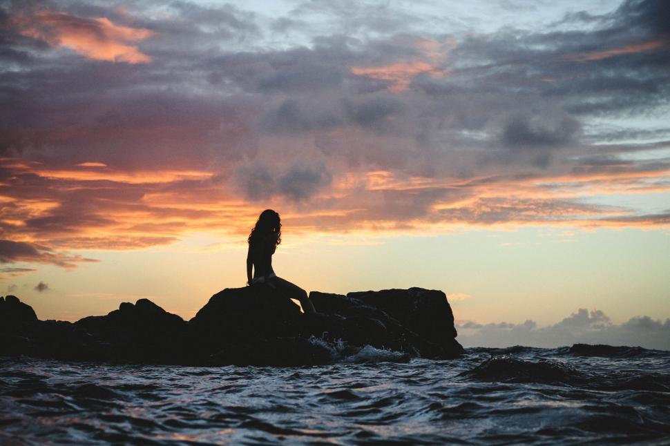 Free Image of Woman Sitting on Rock in Ocean 