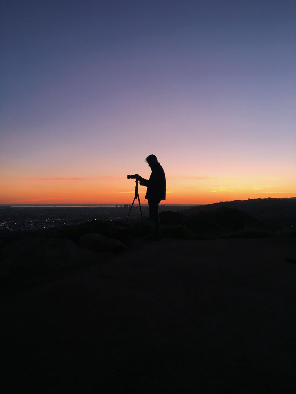 Free Image of Man Standing on Top of Hill Holding Camera 