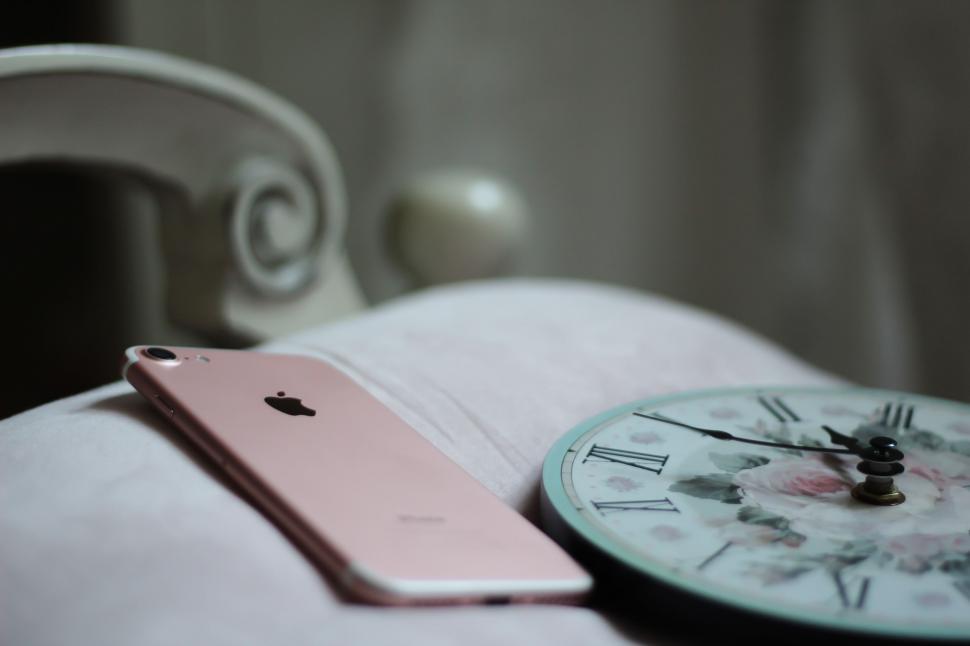 Free Image of Iphone and Clock Placed on a Bed 