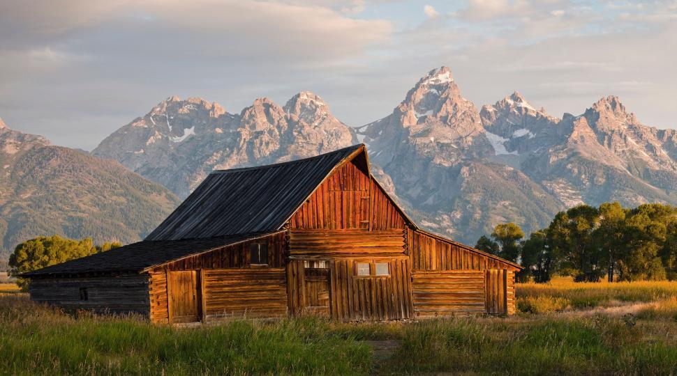 Free Image of Barn in Field With Mountains in Background 