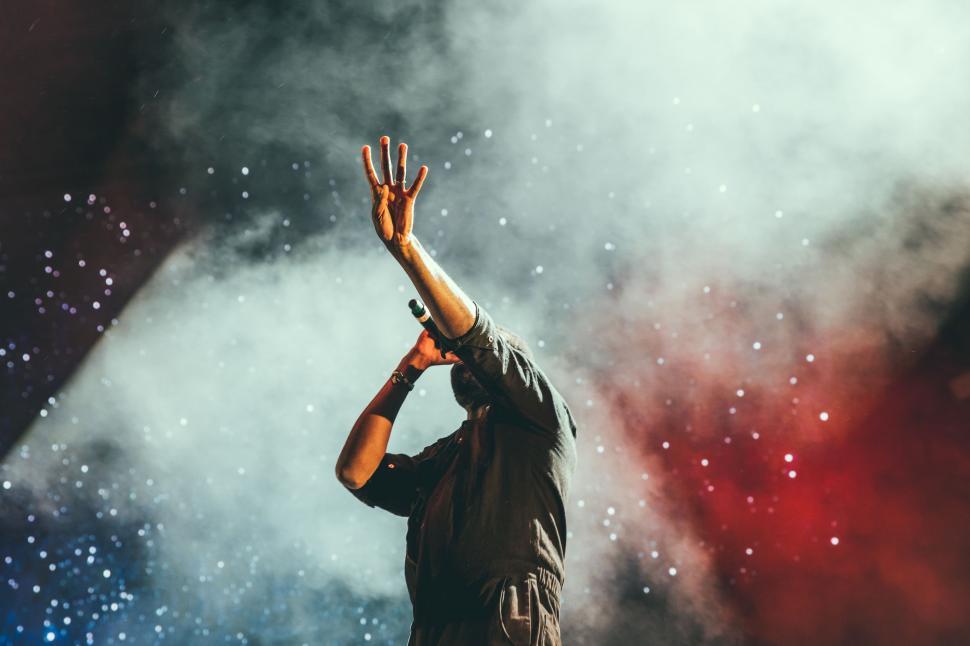 Free Image of Man Standing on Stage With Hands Raised High 