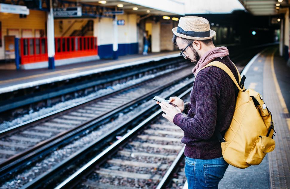 Free Image of Man With Yellow Backpack Using Cell Phone 