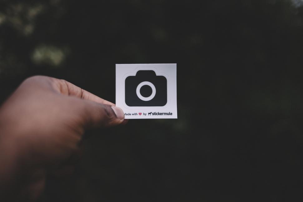 Free Image of Person Holding Up Sticker With Camera Icon 