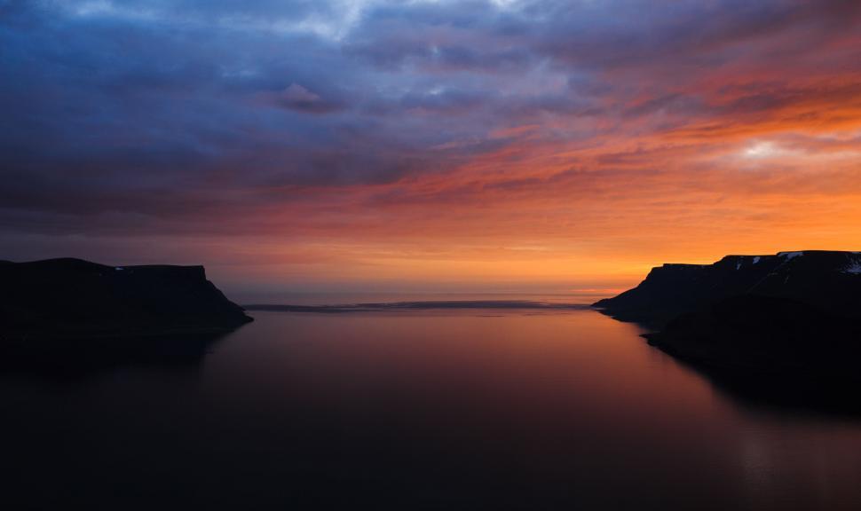 Free Image of Sunset Over Water With Cliffs in Background 