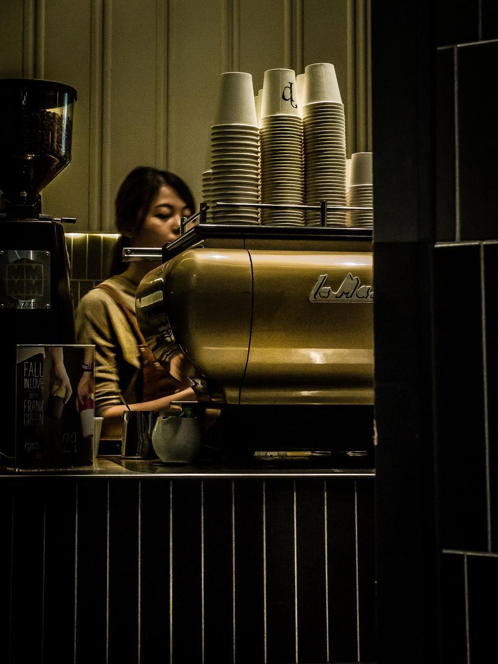Free Image of Woman Sitting at Counter in Front of Coffee Maker 