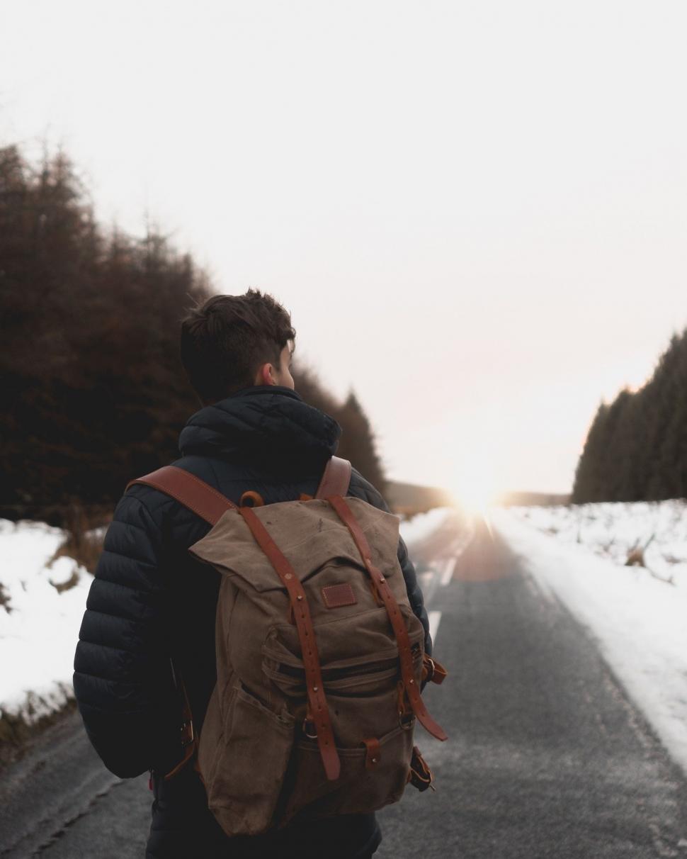 Free Image of Man Walking With Backpack on Snowy Road 
