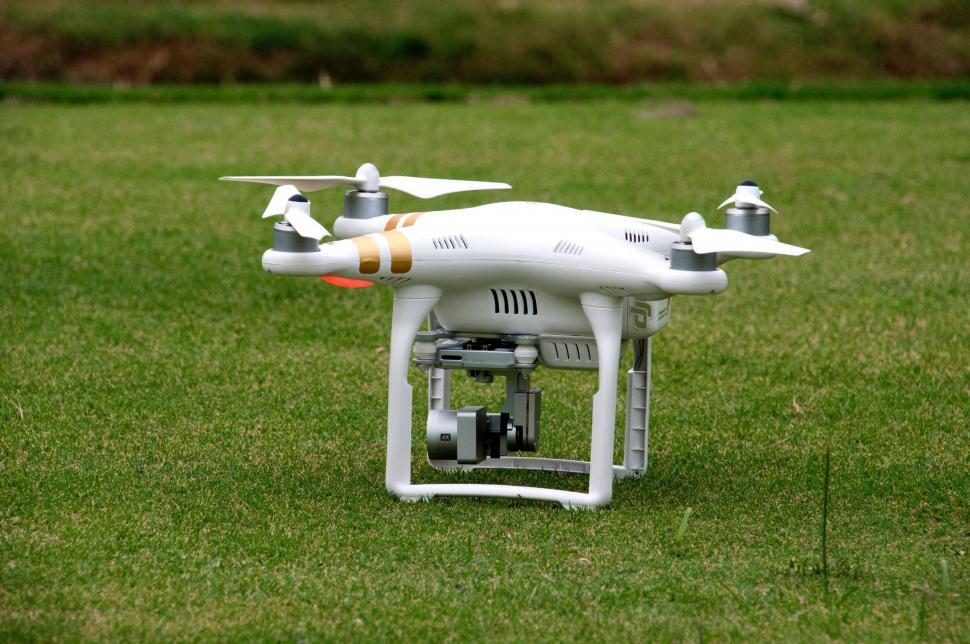 Free Image of White Remote Controlled Drone Flying Above Lush Green Field 