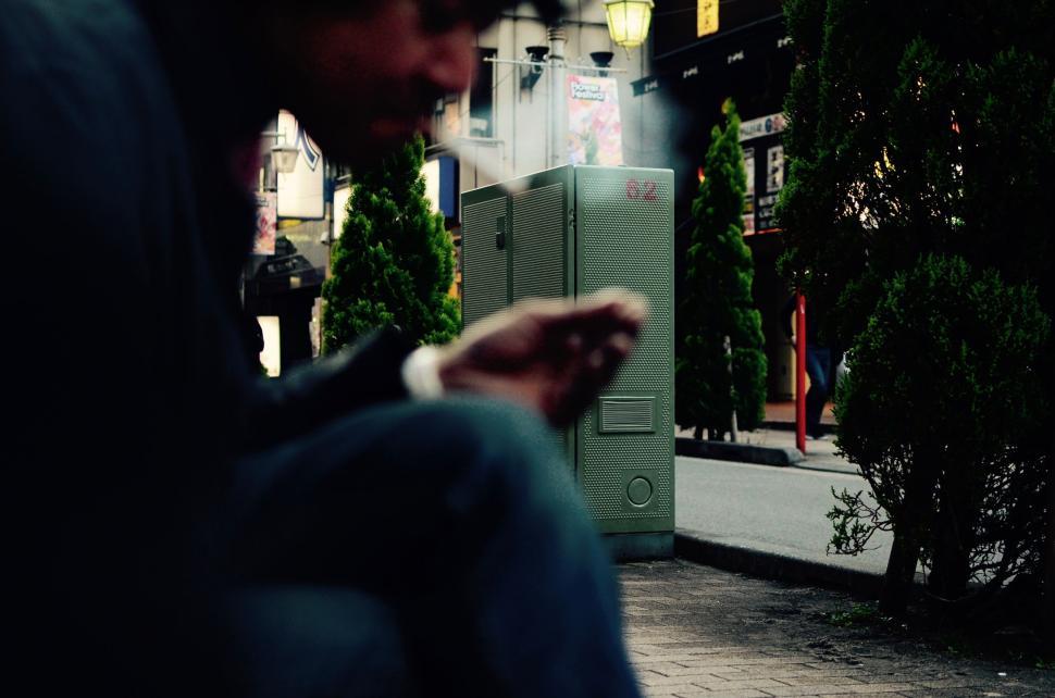 Free Image of Man Sitting on Bench Looking at Cell Phone 