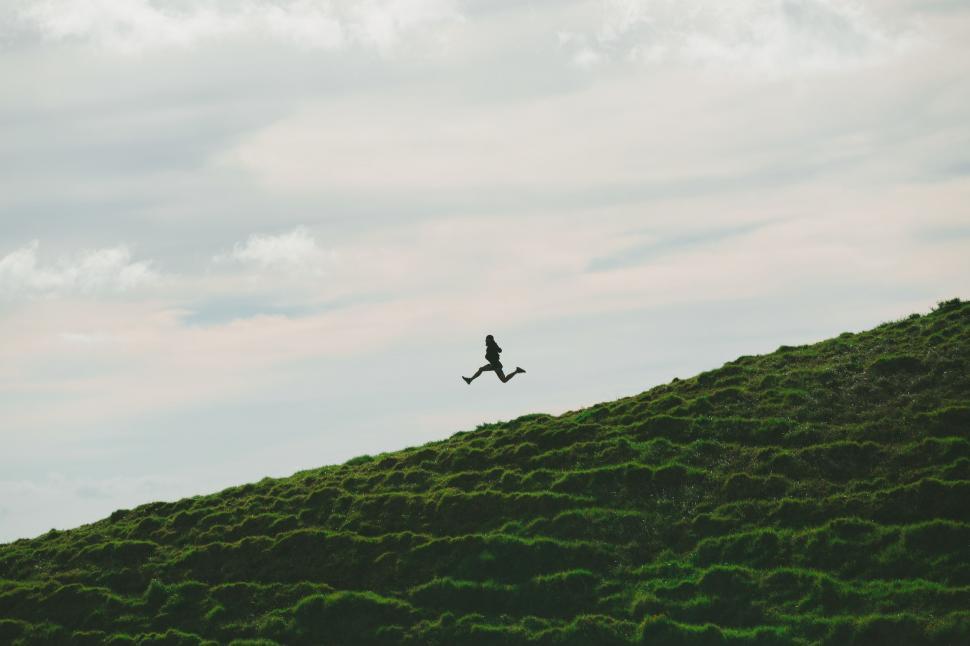 Free Image of Man Flying Kite on Lush Green Hillside 