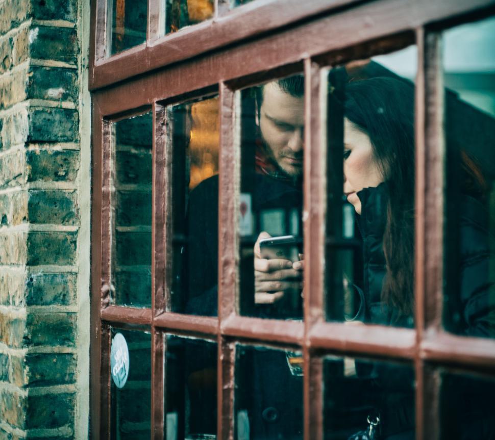 Free Image of Man and Woman Looking Out of a Window 