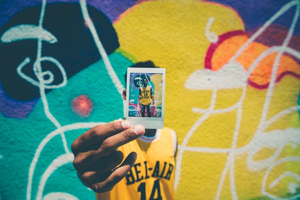 Free Image of Person Holding Cell Phone in Front of Graffiti Wall 