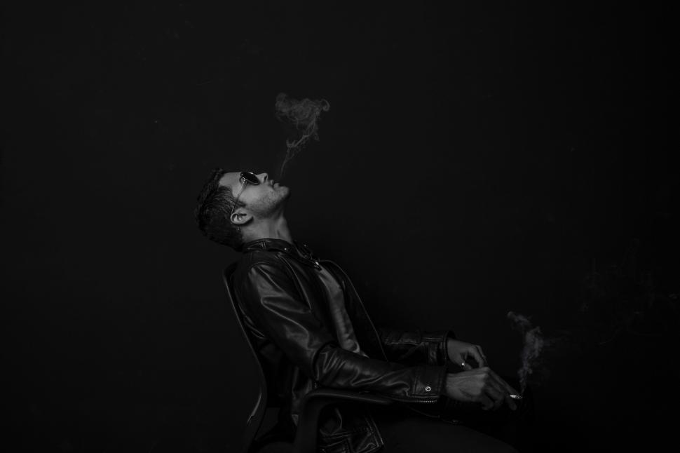 Free Image of Man Sitting in Chair Smoking Cigarette 