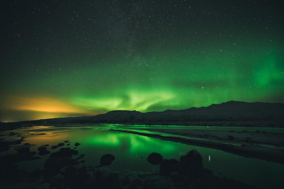 Free Image of Green and Yellow Aurora Dancing Over Body of Water 