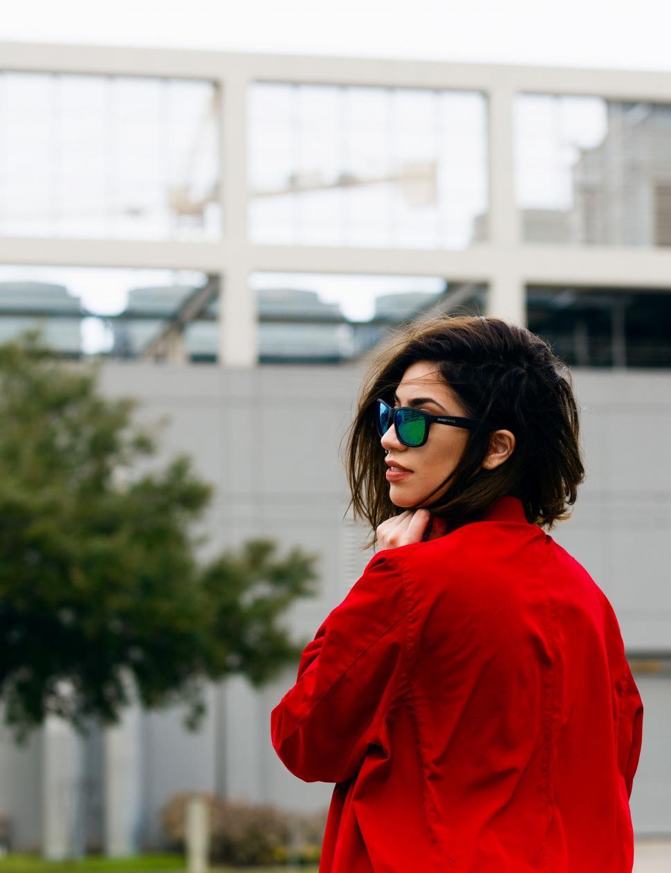 Free Image of Woman in Red Jacket and Sunglasses Talking on Cell Phone 
