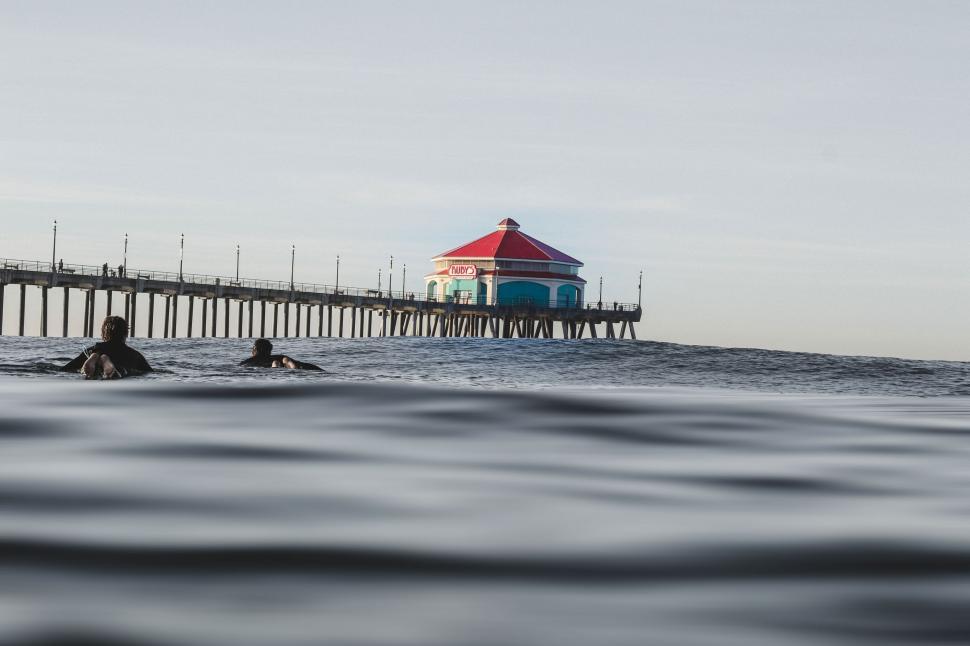Free Image of Group of People Swimming in Ocean Near Pier 