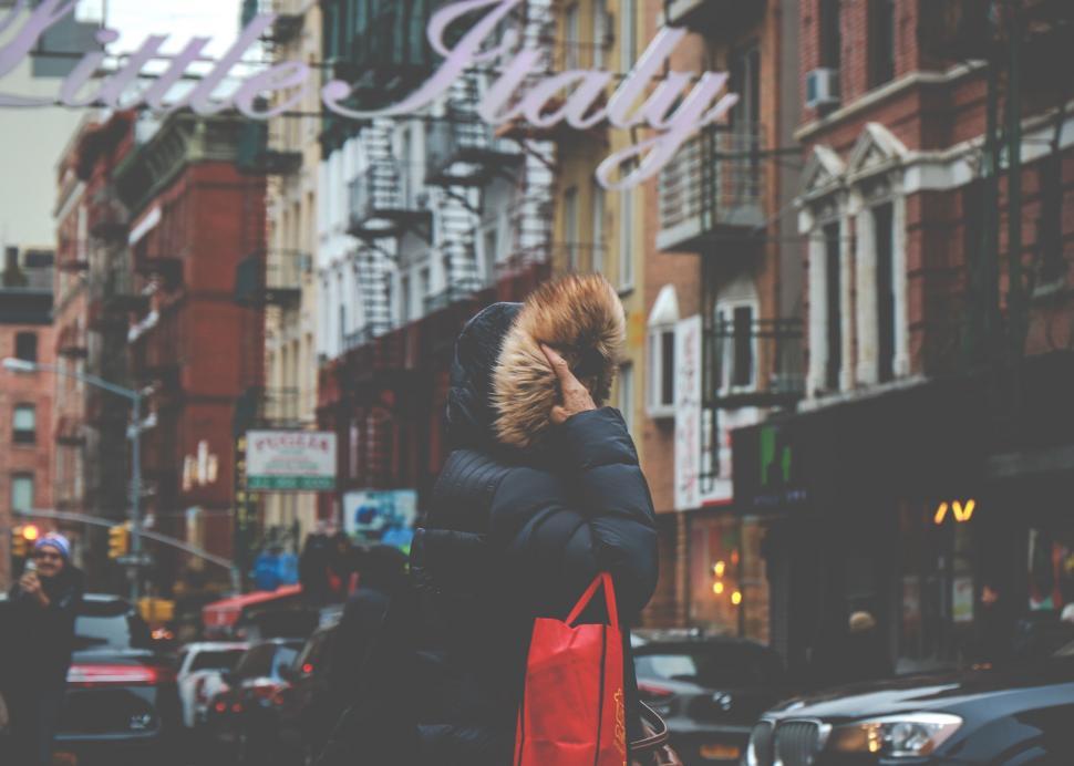 Free Image of Woman Walking Down a Street With a Red Bag 