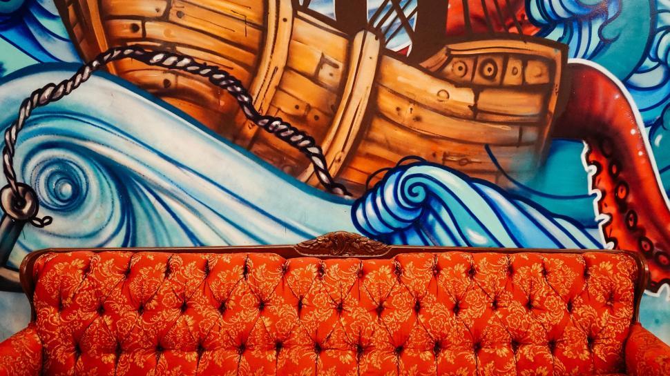 Free Image of Couch in Front of Ship Painting 